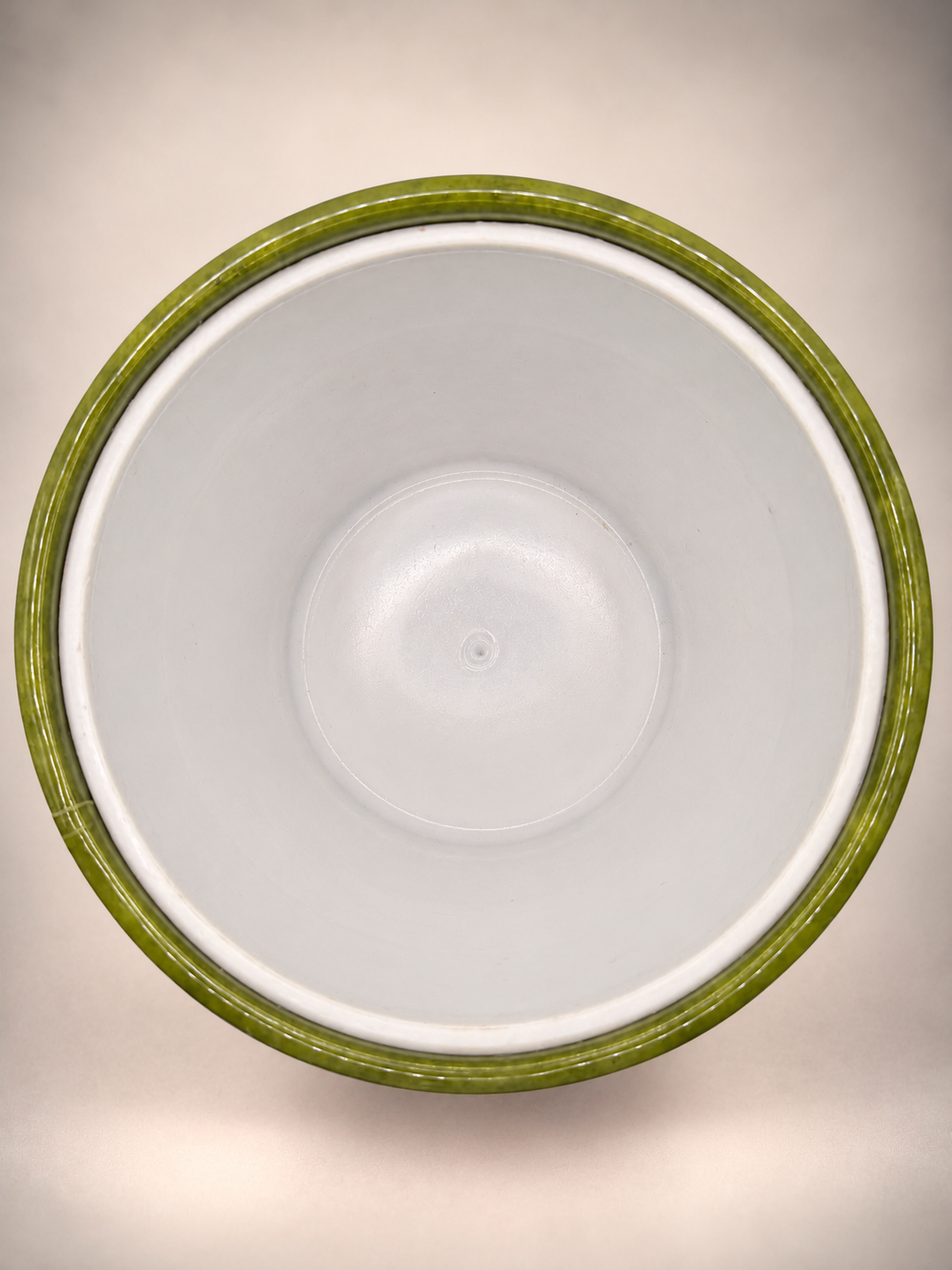 Overhead view of white interior liner inside an avocado-green Irvinware ice bucket showing light signs of previous use.