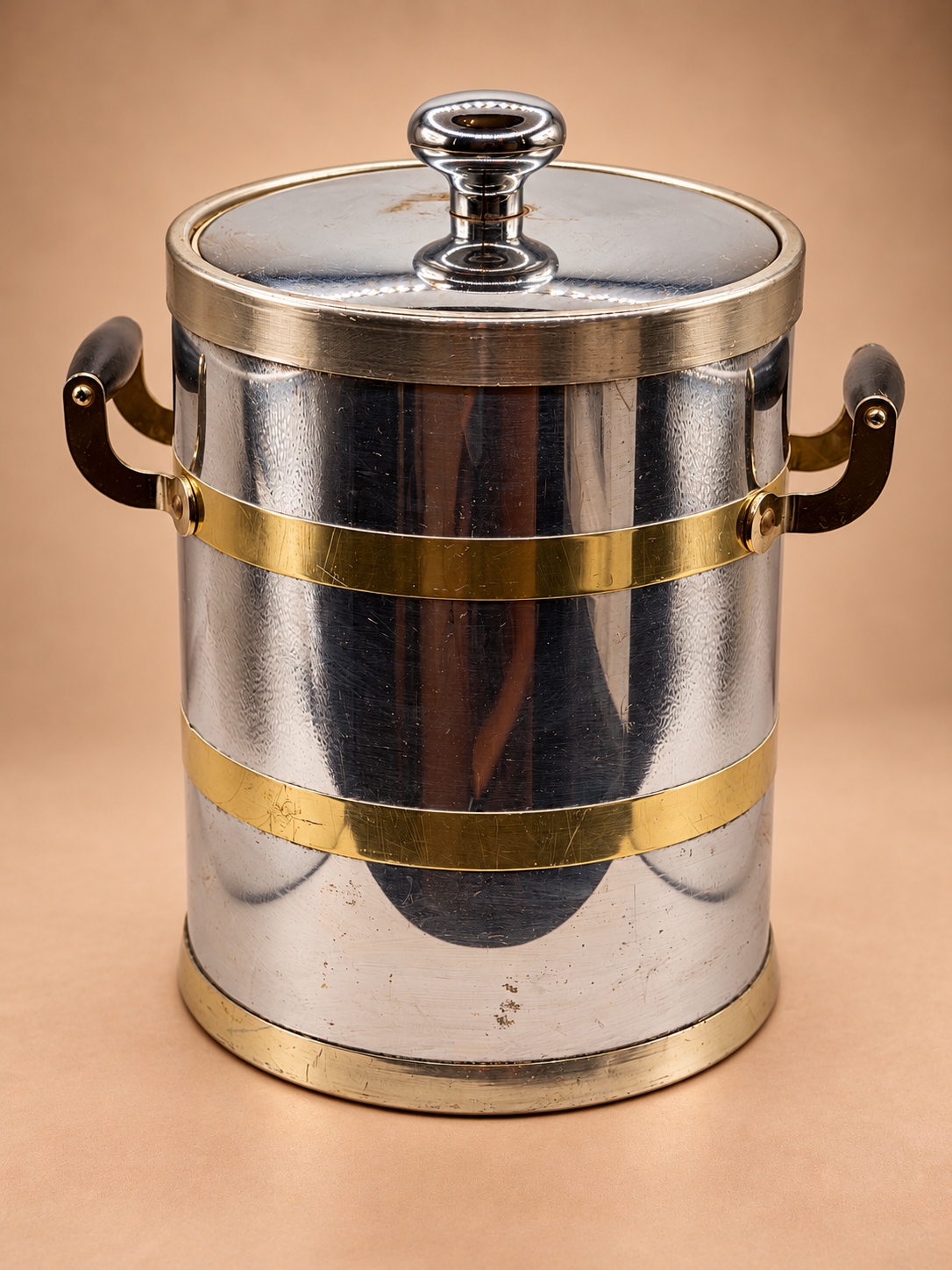 Vintage Kraftware N.Y.C. ice bucket with reflective silver-tone body, gold bands, dark side handles and fitted lid.