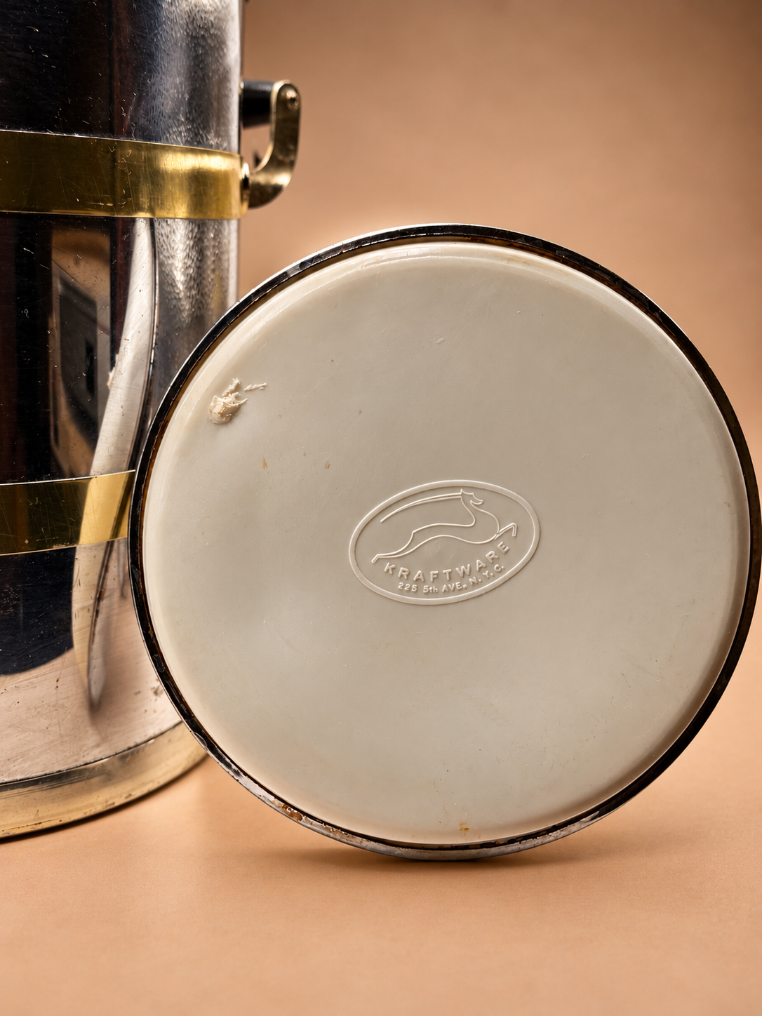 Underside of vintage Kraftware ice bucket lid showing white liner and embossed Kraftware leaping-deer maker mark.