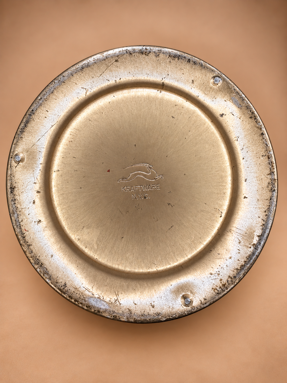 Bottom of vintage ice bucket showing stamped Kraftware N.Y.C. maker mark and vintage surface wear.