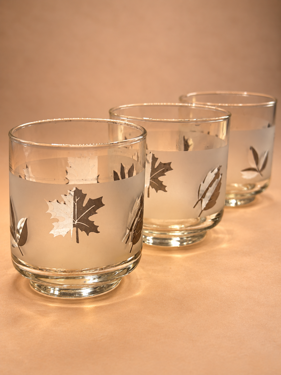 Four vintage midcentury Libbey rocks glasses featuring frosted glass bands and reflective silver leaf designs.