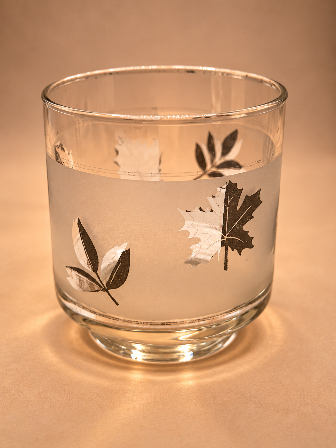 Close-up of vintage Libbey rocks glass showing intact frosted band and metallic silver maple and foliage decoration.