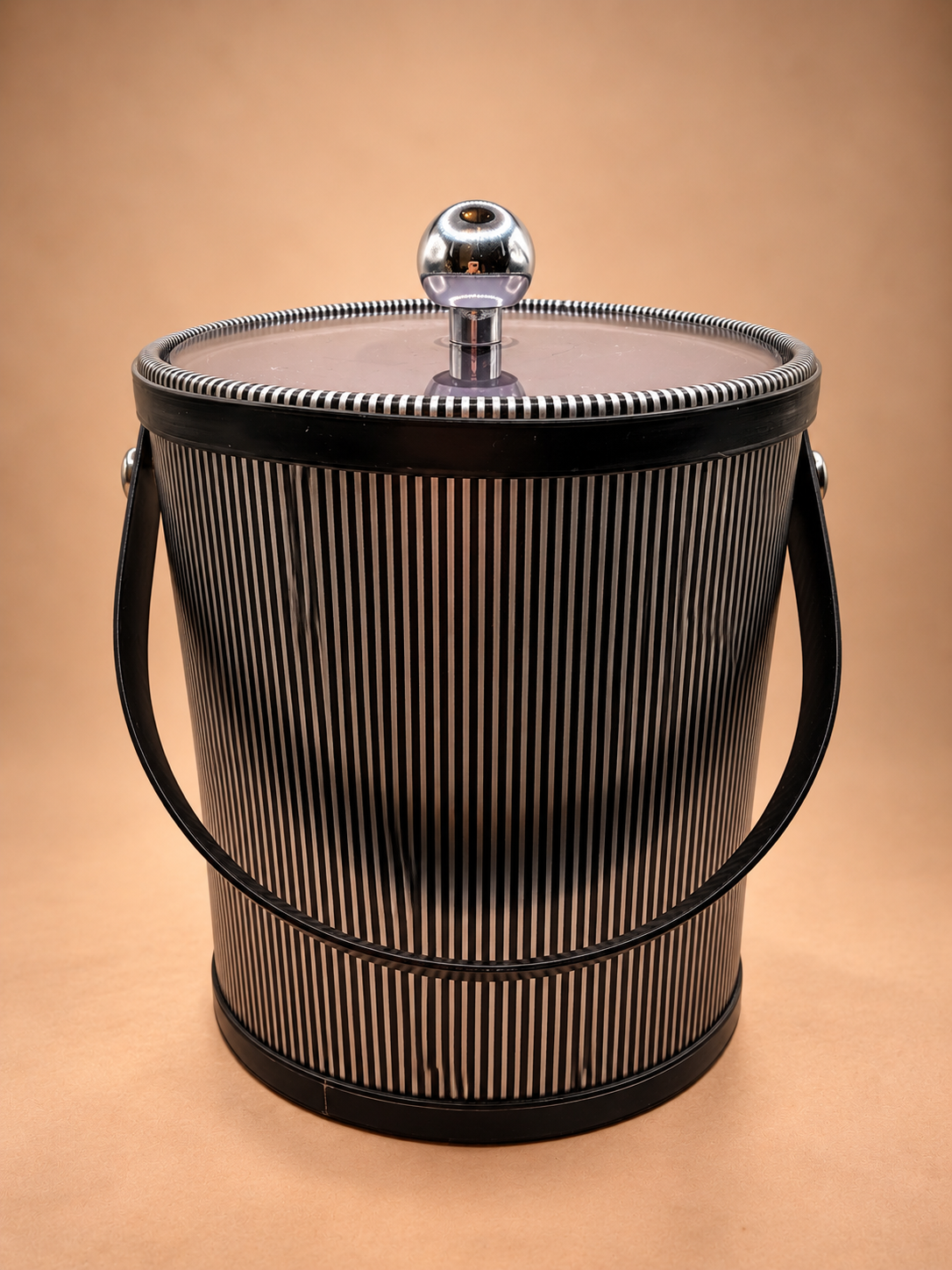 Vintage midcentury striped ice bucket with black swing handle, silver-tone knob and translucent tinted lid.
