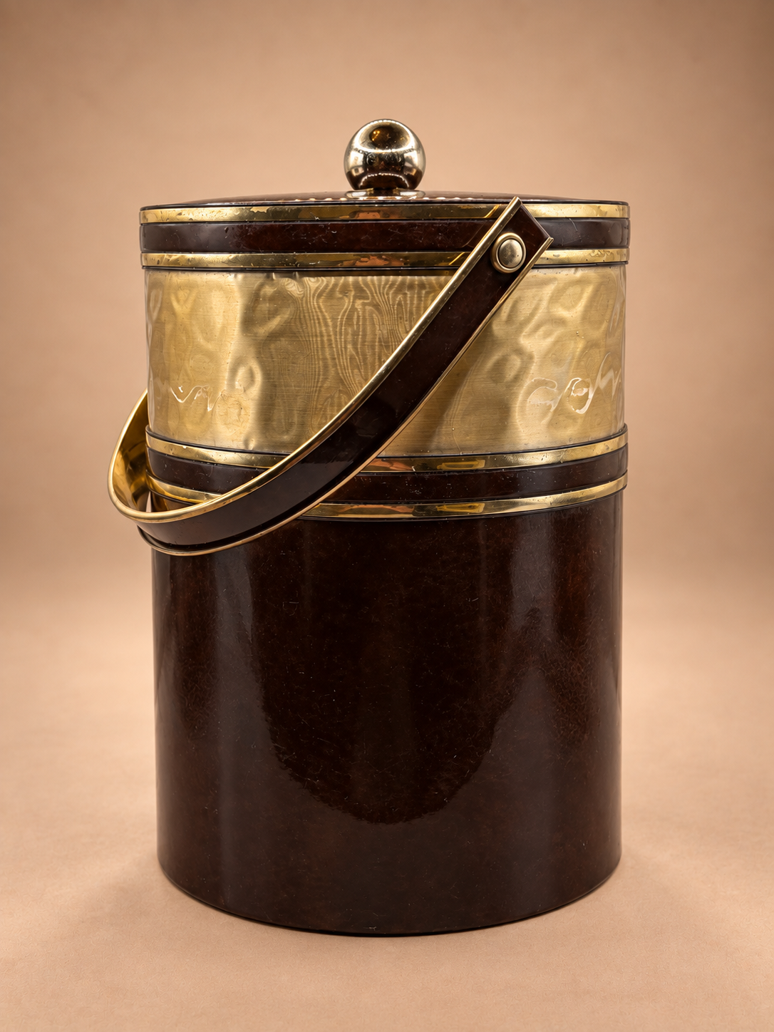 Vintage midcentury ice bucket with glossy brown tortoiseshell-style finish, brushed gold band, gold-tone trim and swing handle.