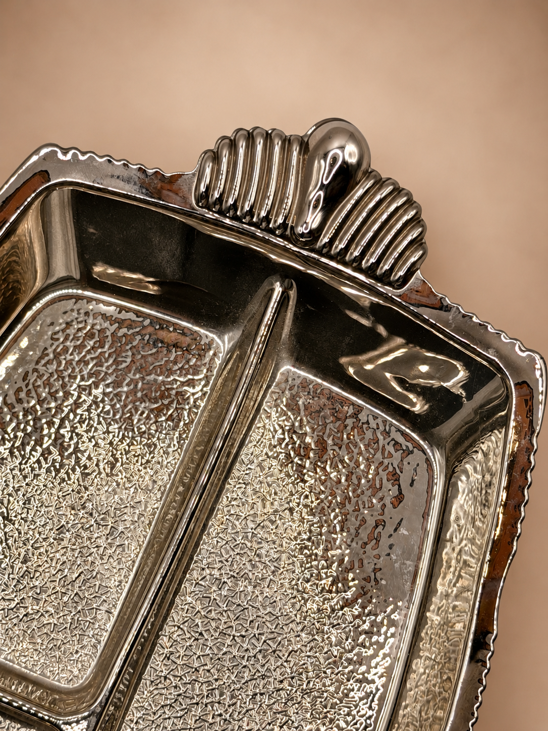 Close-up of sculptural ribbed handle and silver-tone finish on vintage divided glass relish serving dish.