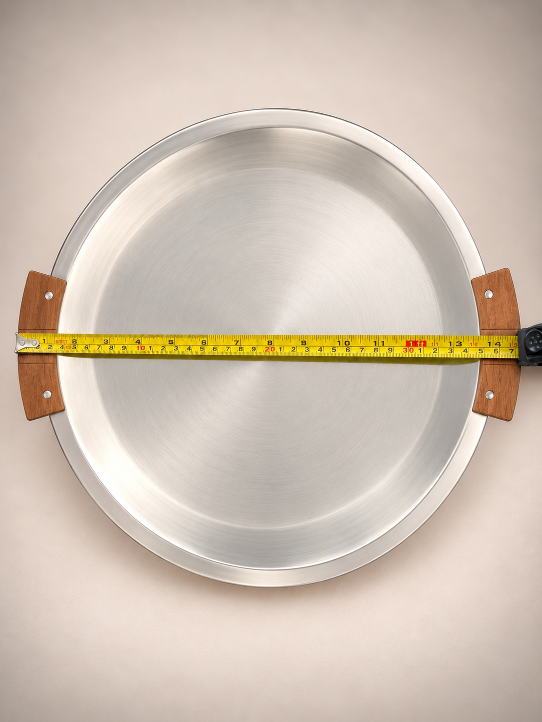 Overhead view of vintage round metal serving tray with wooden handles and measuring tape showing approximately 17-inch overall width.