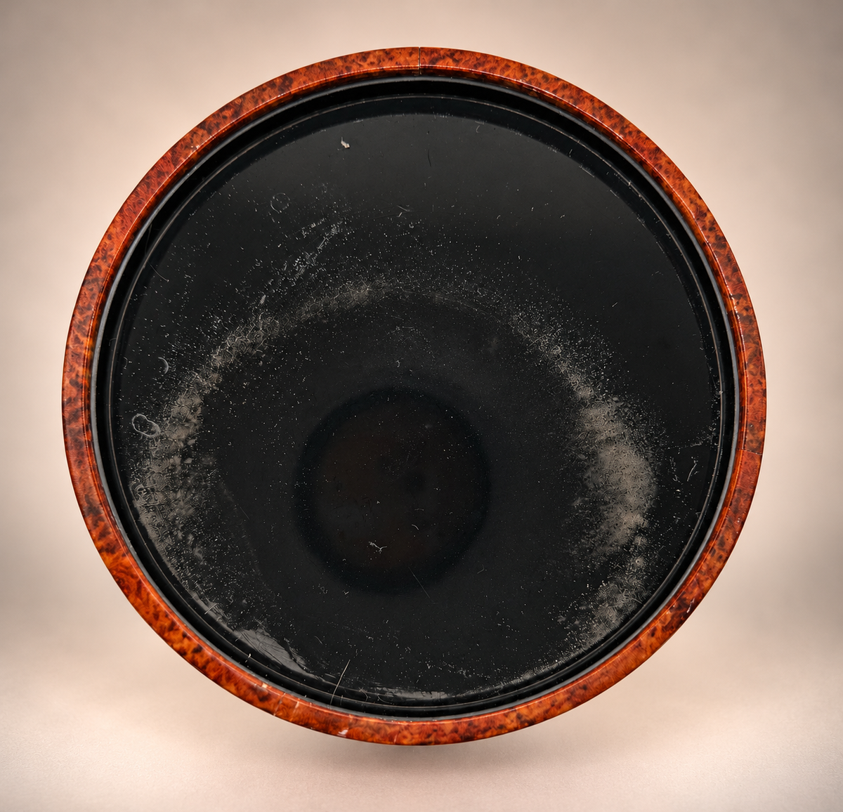 Bottom of vintage brown ice bucket showing circular scuffing, scratches and surface wear on black base.