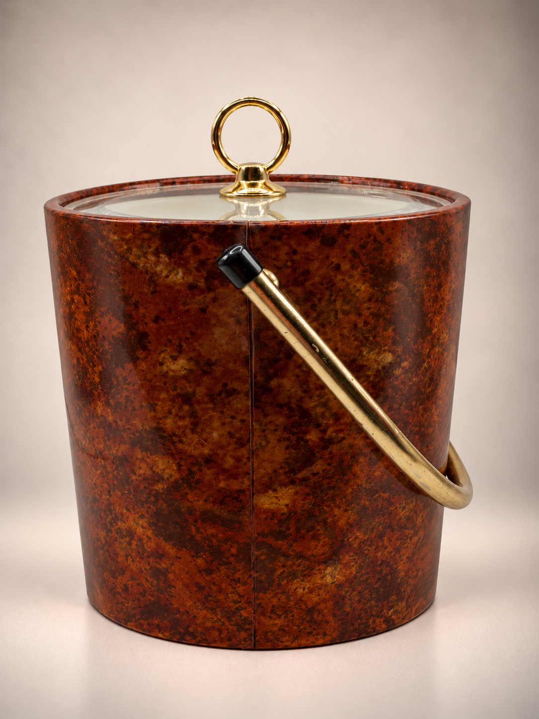 Vintage brown tortoiseshell-style ice bucket with gold-tone swing handle, clear lid and circular gold pull.