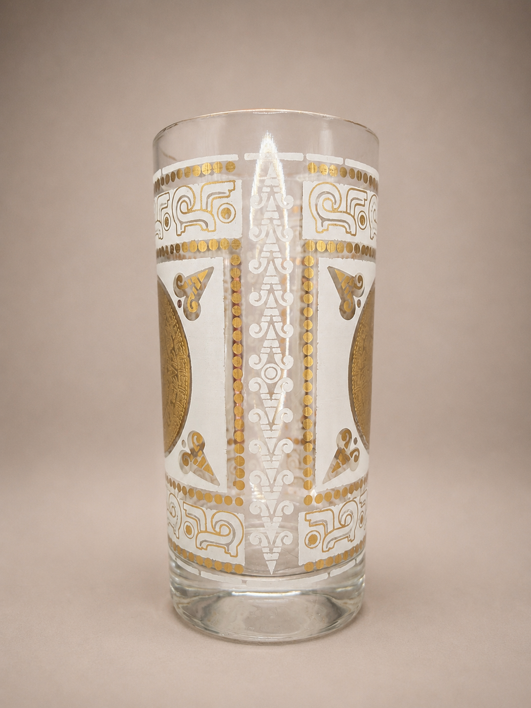 Side view highlighting the wraparound white and metallic gold geometric decoration on a vintage highball glass.