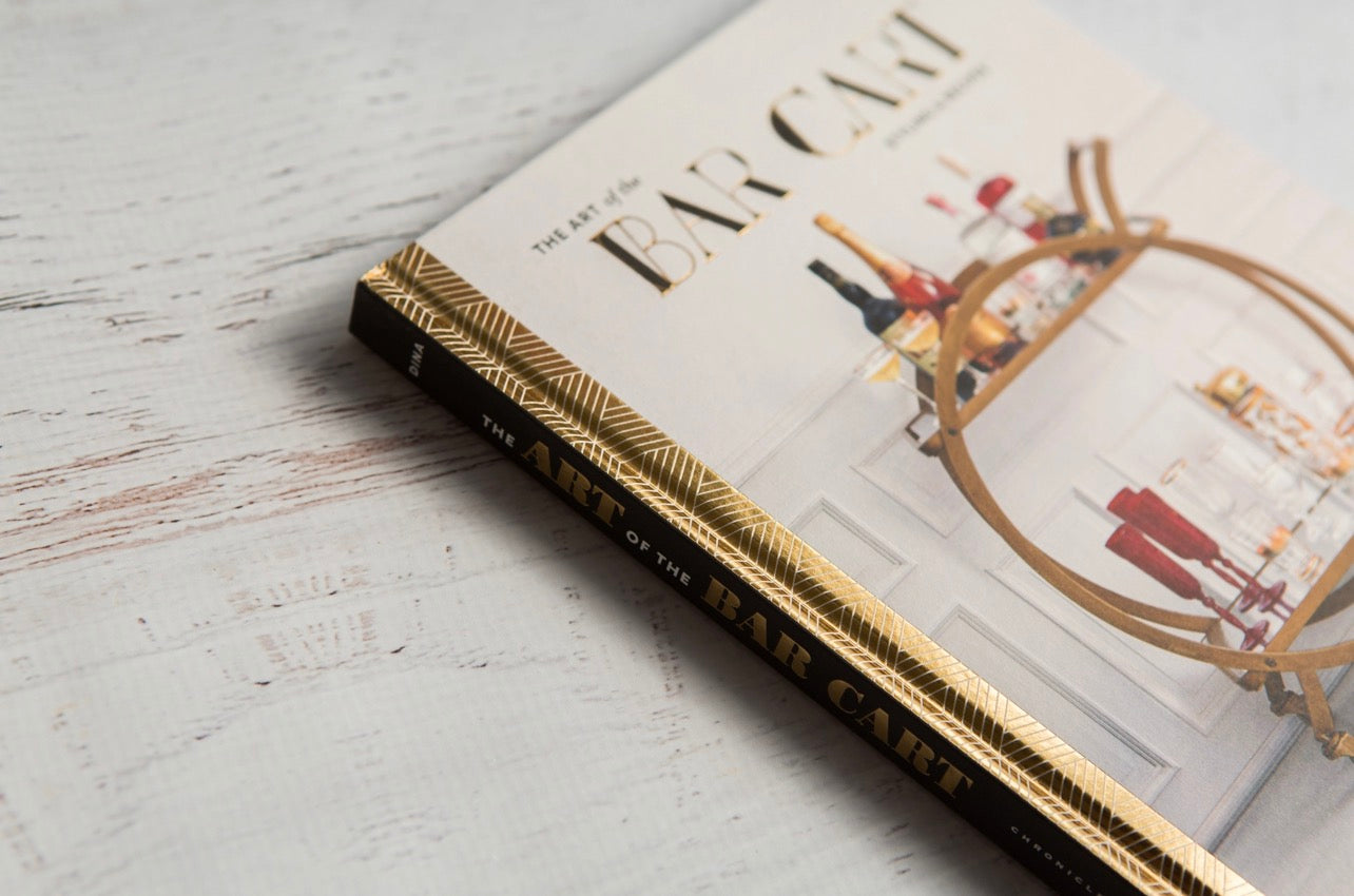 Close-up of The Art of the Bar Cart book showing the gold-patterned spine and cover detail, a stylish gift for cocktail lovers.