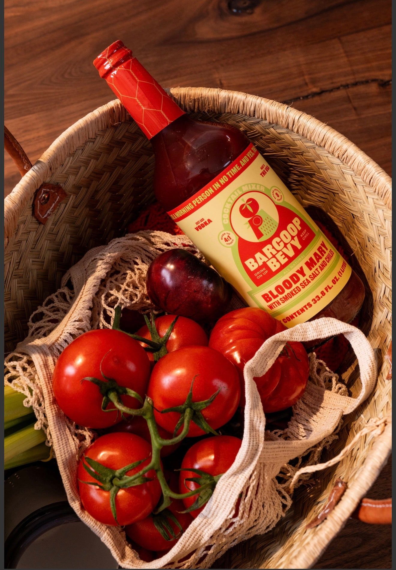 Barcoop Bevy Bloody Mary mix bottle in basket with fresh tomatoes and produce lifestyle scene