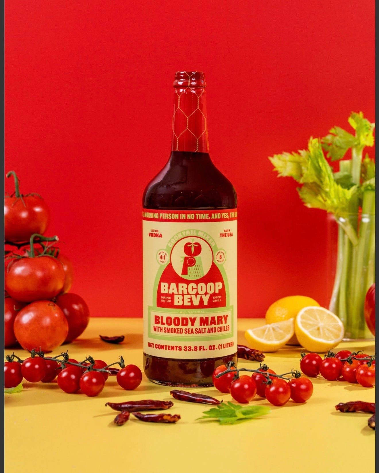 Barcoop Bevy Bloody Mary mix with fresh tomatoes celery lemon and chiles on red background