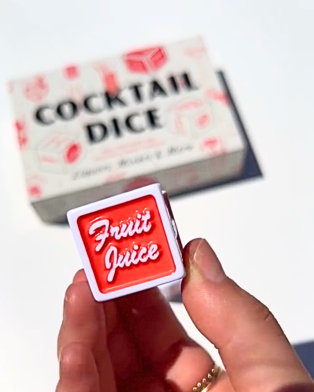 Close-up of the “Fruit Juice” cocktail dice held in hand, part of a fun cocktail dice game for cocktail lovers and home bartenders.
