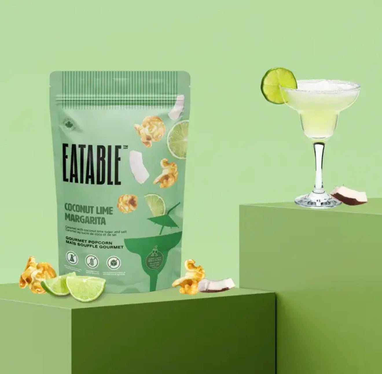Coconut Lime Margarita popcorn bag styled on green pedestal beside margarita cocktail