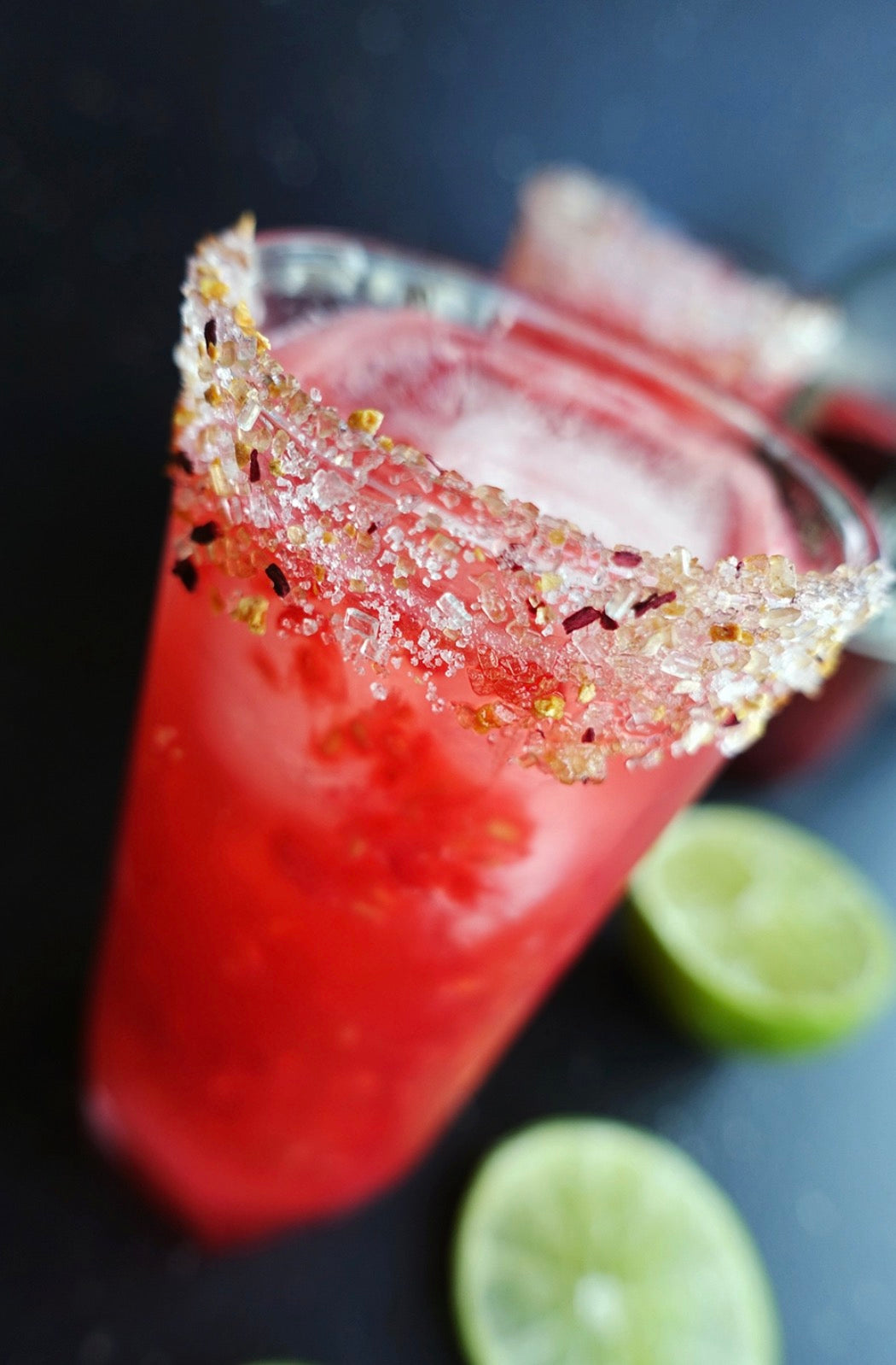 Cranberry cocktail with sparkling berry sugar rim and lime garnish using rokz Cranberry Cocktail Sugar.
