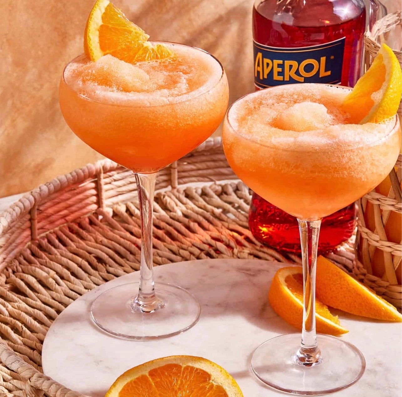 Frozen Aperol Spritz cocktails served in coupe glasses with orange garnish for entertaining