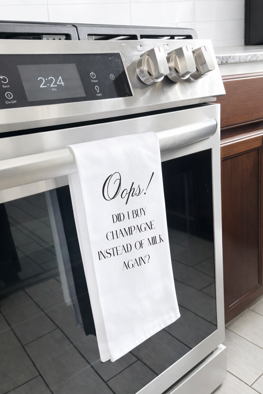Funny champagne kitchen towel hanging on oven handle in modern kitchen