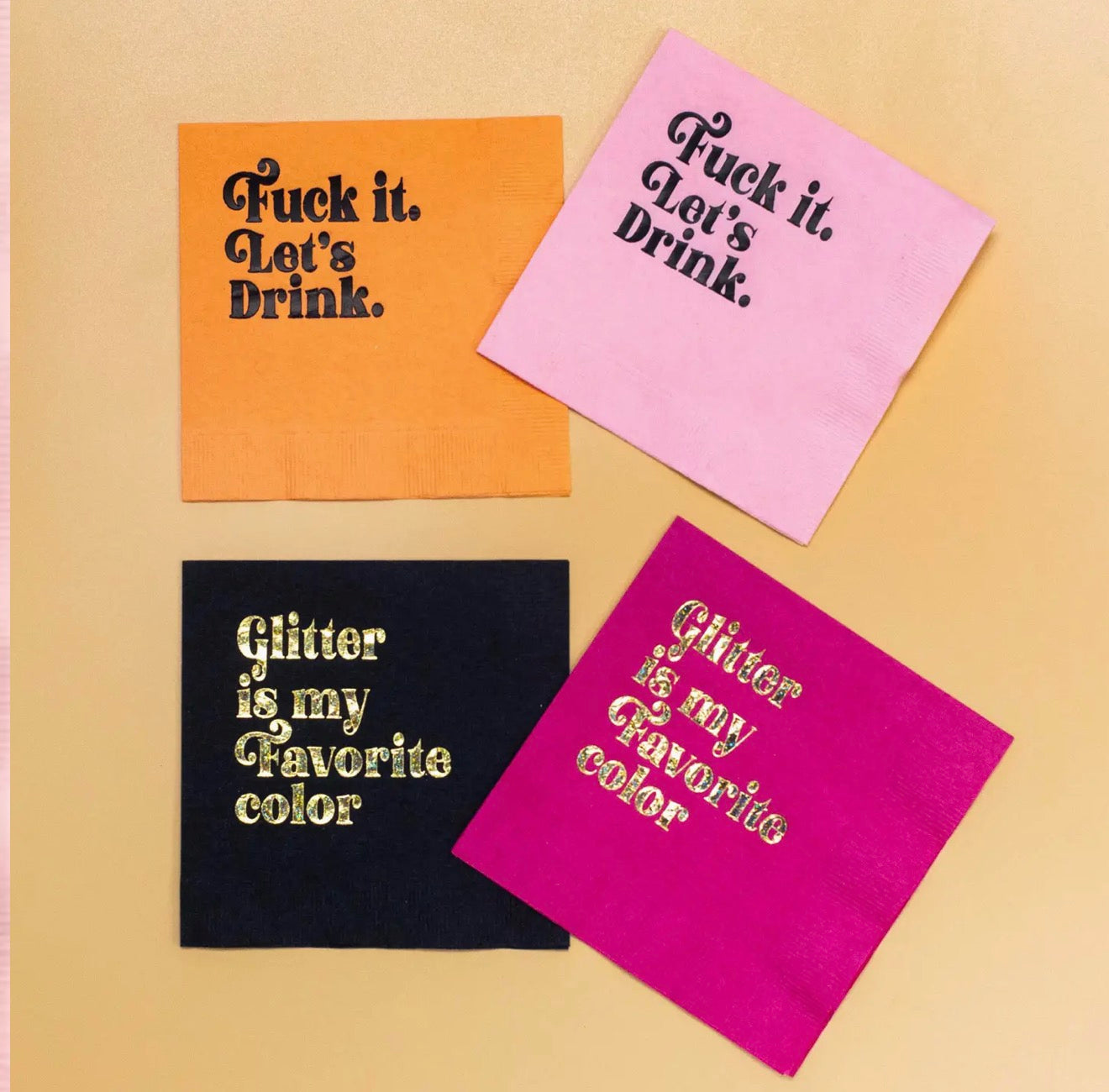 Assorted colorful cocktail napkins including pink Fuck It Let’s Drink party napkins flat lay