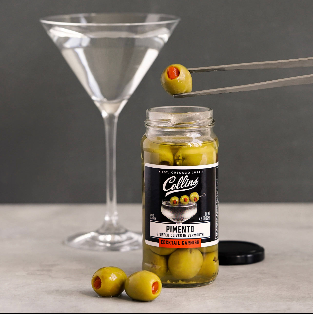 jar of pimento stuufed olives in vermouth displayed with a martini cocktail