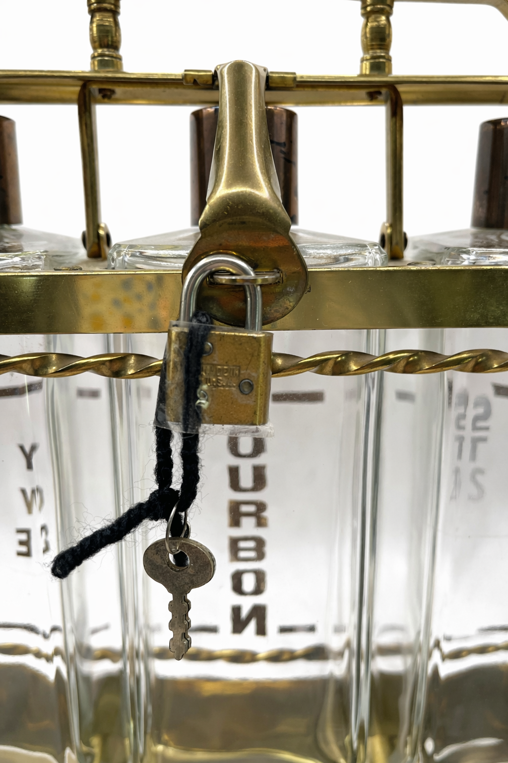 Front view of vintage brass decanter set locked with key labeled Bourbon Rye Scotch