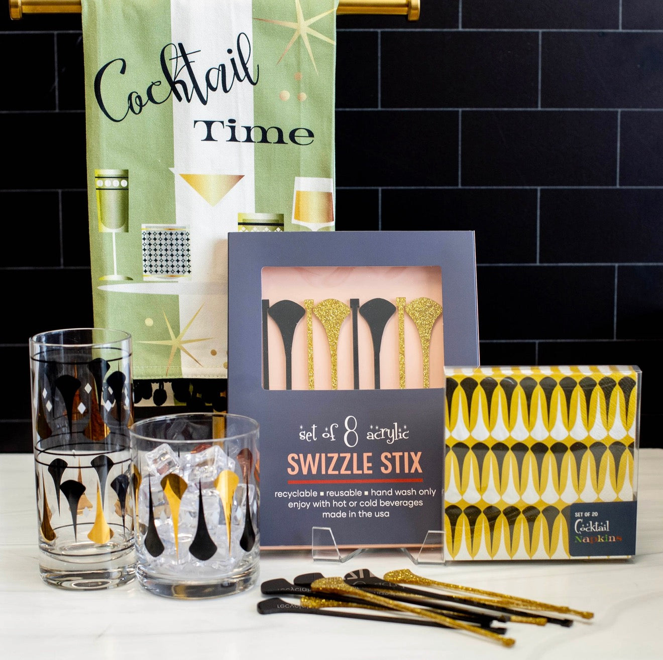 Mid century modern cocktail napkins styled with matching glasses, swizzle sticks, and bar accessories.