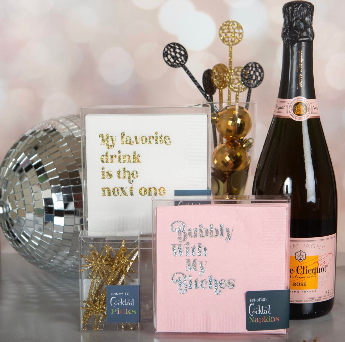 Funny gold foil cocktail napkins styled with champagne bottle disco ball and cocktail accessories