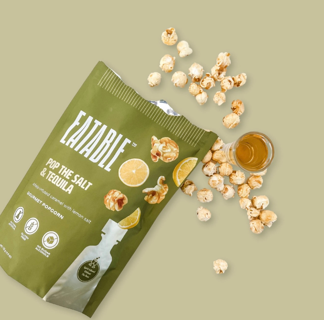 Open bag of Pop the Salt and Tequila popcorn with scattered popcorn and shot glass