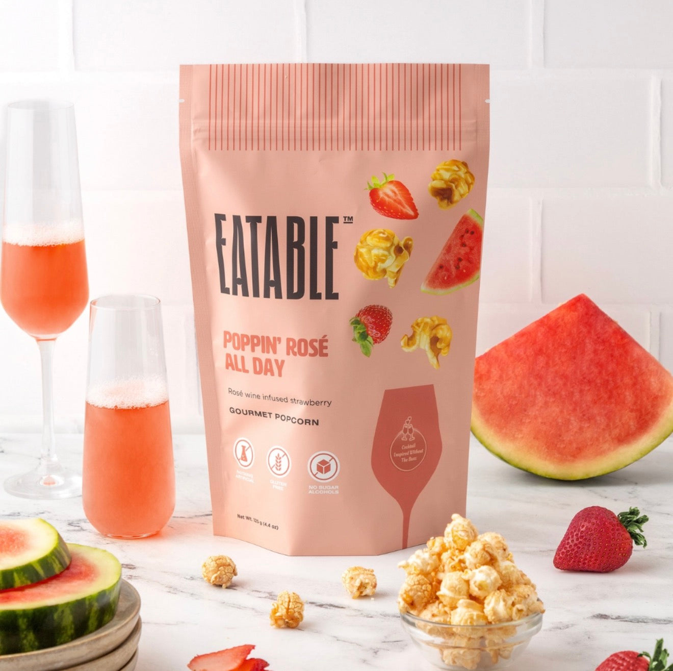 Eatable Poppin Rosé All Day gourmet popcorn bag styled with rosé drinks, strawberries, watermelon, and popcorn