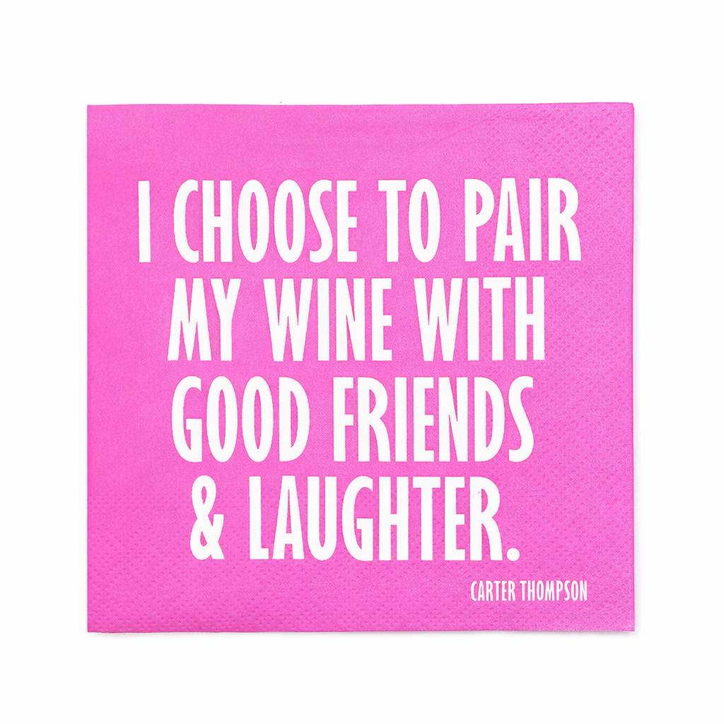 Pink cocktail napkin with white lettering that reads “I Choose to Pair My Wine with Good Friends and Laughter” by Carter Thompson displayed on a white background.
