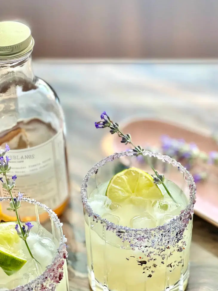 glasses of lemonade garnished with lemon and lavender with the french lavender finishing sugar rimming the glass