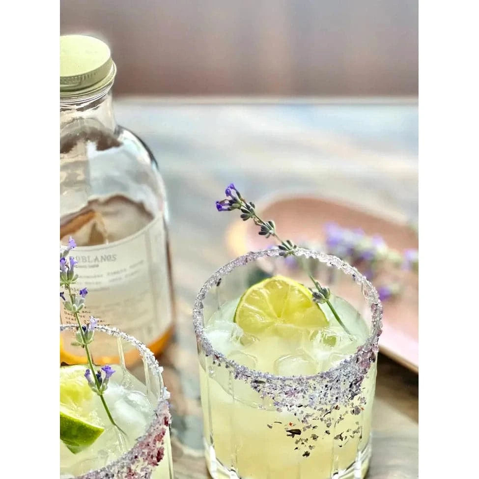 glasses of lemonade garnished with lemon and lavender with the french lavender finishing sugar rimming the glass