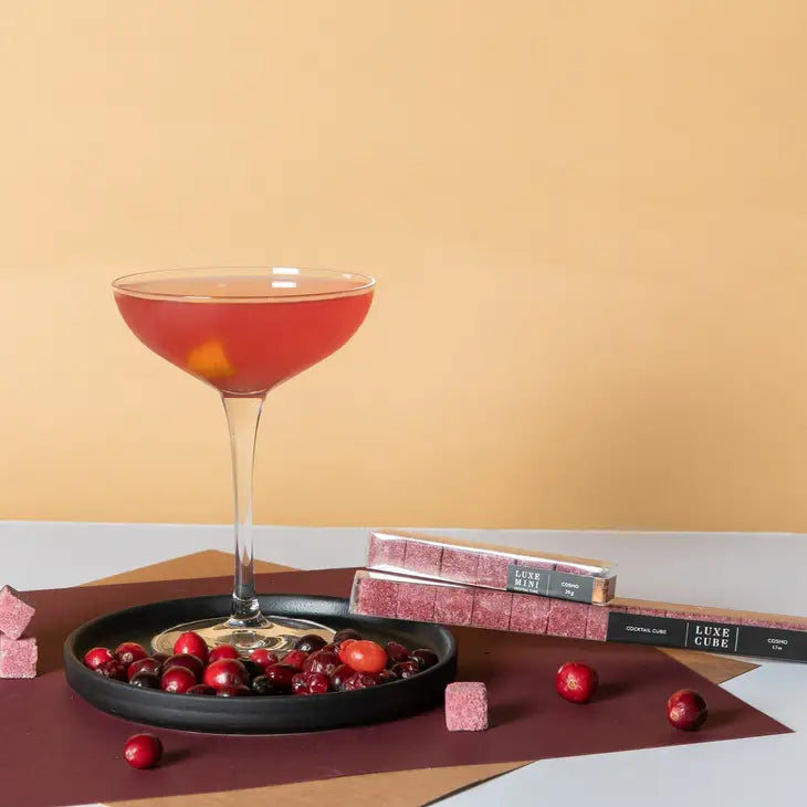instant cocktail cubes displayed with a cocktail in a martini glass surrounded by cranberries