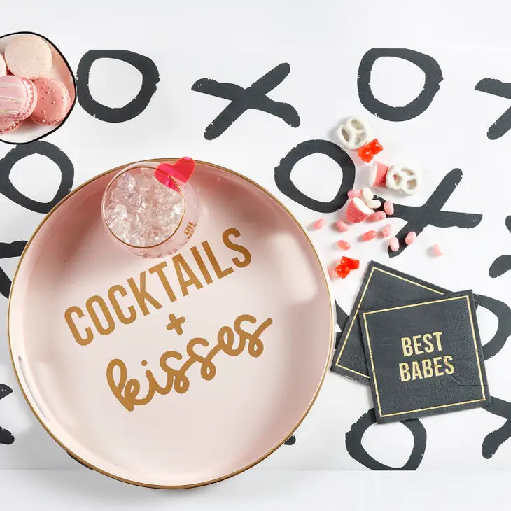 5" x 5" square black paper napkin with a gold foil square border and the words "best babes" in gold foil in the center displayed with a pink bar tray with cocktail and candies are scattered on the table