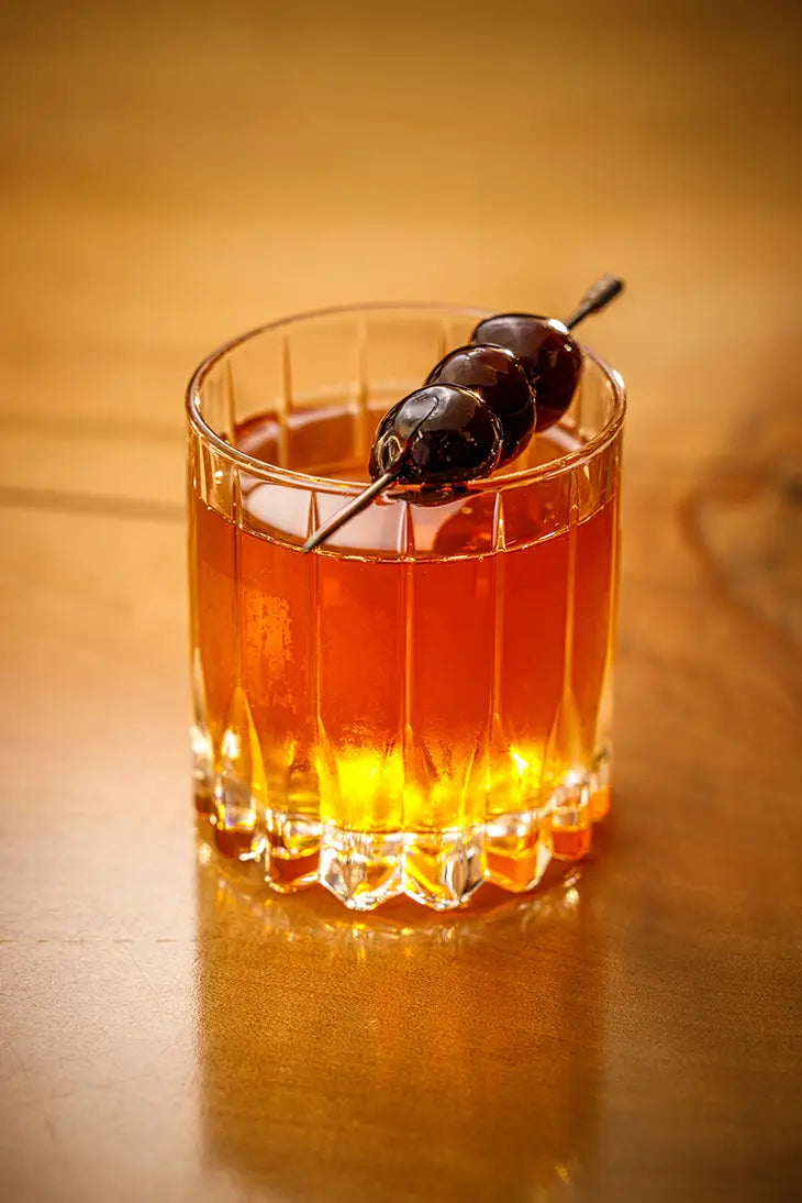 old fashioned cocktail garnished with cherries