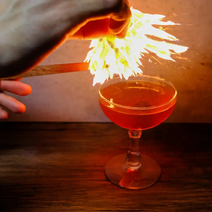 cedar being lit over a cocktail 
