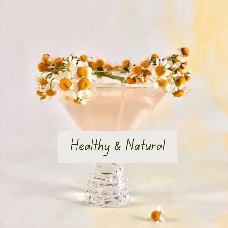 soft golden colored shimmering cocktail in a clear martini glass decorated with flowers on top with the statement saying "health and natural"