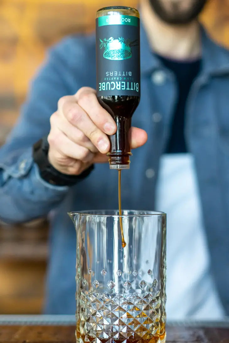1.7 oz bottle of root beer flavored bitters by Bittercube being poured into a mixing glass